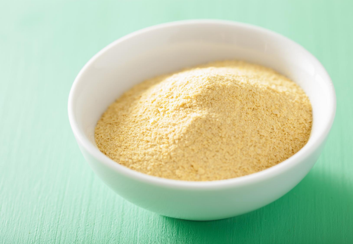 Bowl of Nutritional Yeast on Green Background