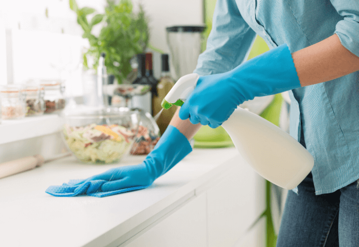 Person disinfecting kitchen surfaces with a spray bottle